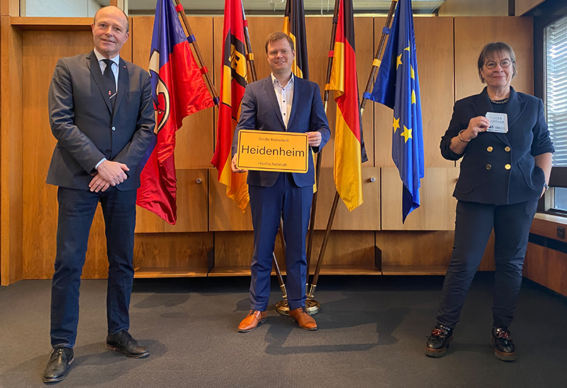 Foto von links nach rechts: Prof. Dr. Dr. Rainer Przywara, Rektor der DHBW Heidenheim, Oberbürgermeister Michael Salomo und Bürgermeisterin Simone Maiwald präsentieren einen Entwurf für das das neue Ortsschild mit dem Titel Hochschulstadt