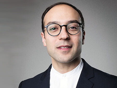 Prof. Dr. Roman Grinbalt Prof. Dr. Roman Grinbalt vor grauem Hintergrund