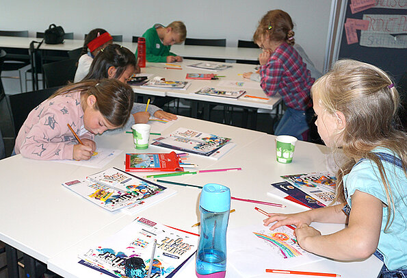 Kinder malen einen Regenbogen im Rahmen der Kinder Uni